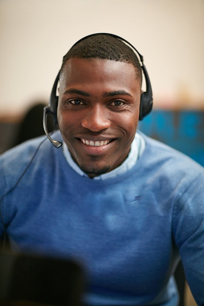 Support specialist wearing a headset, smiling in a professional office setting